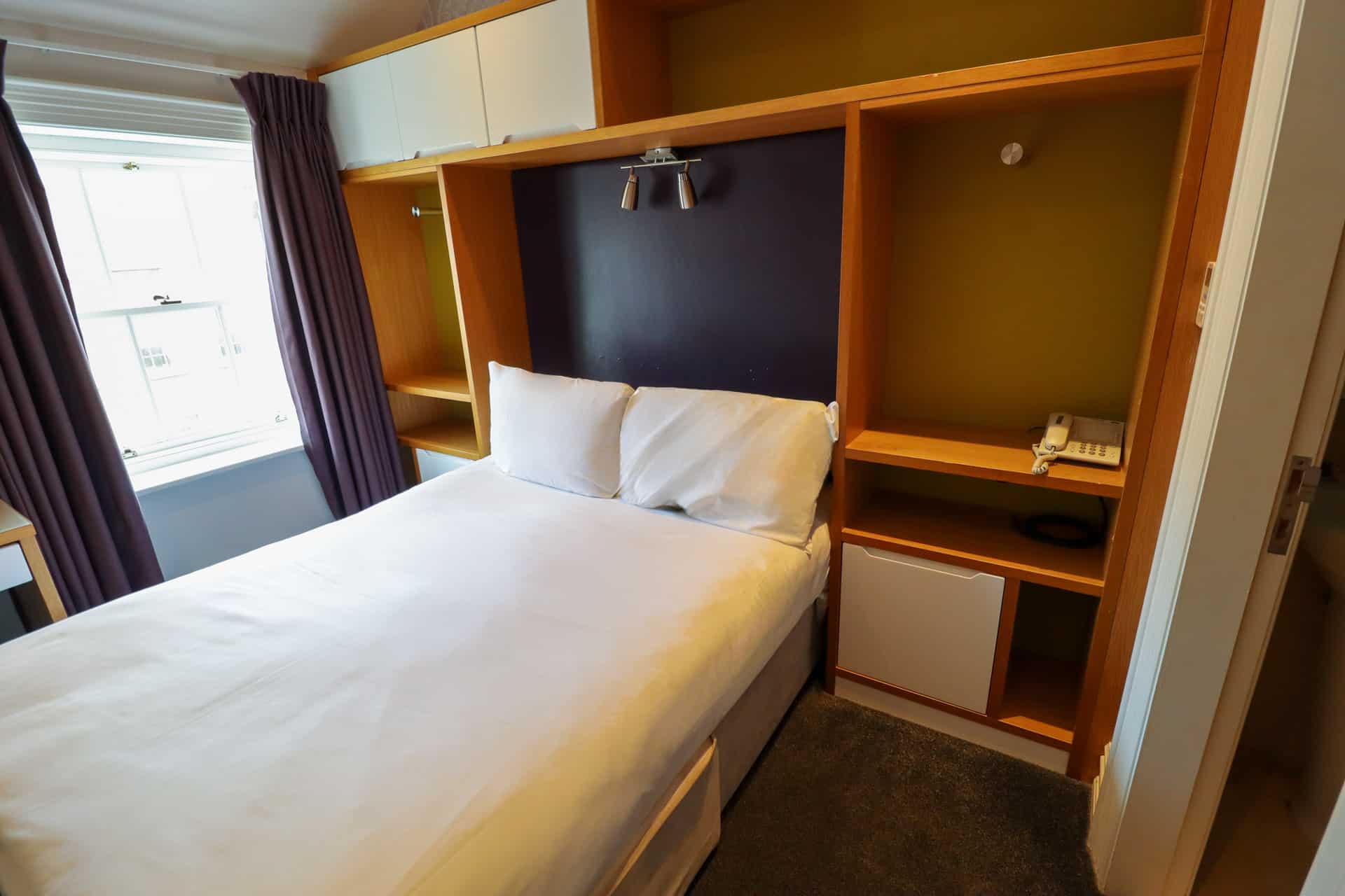 Close up view of the double bed with curtains opened at the Jackson Court Hotel